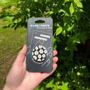 a pop socket with a solid black background with white flowers on it. never used